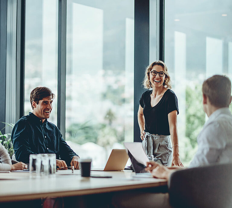 Three people in a mordern office smiling, communicating positively